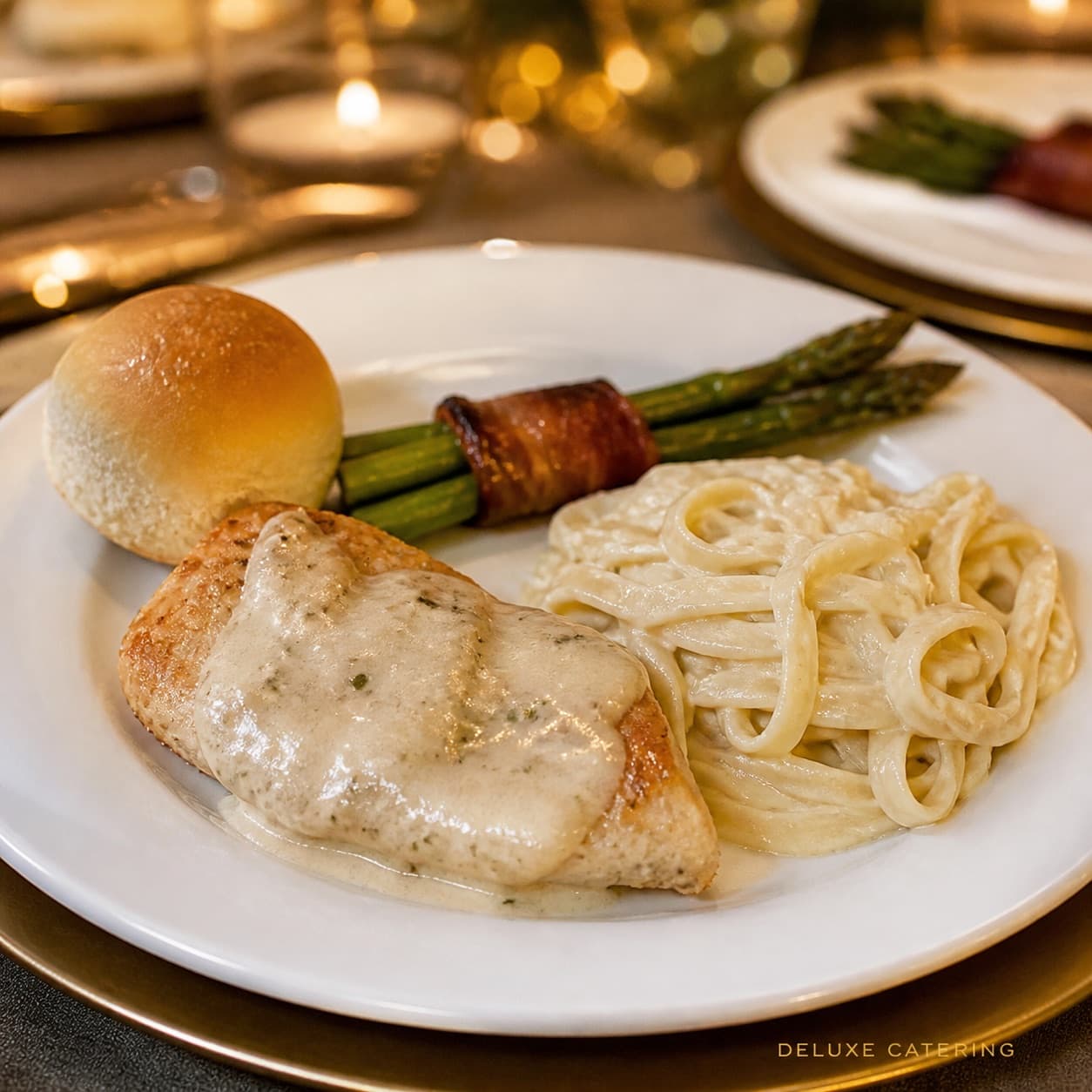 Chicken in cream sauce with fettuccine alfredo and bacon-wrapped asparagus on an elegant candlelit table