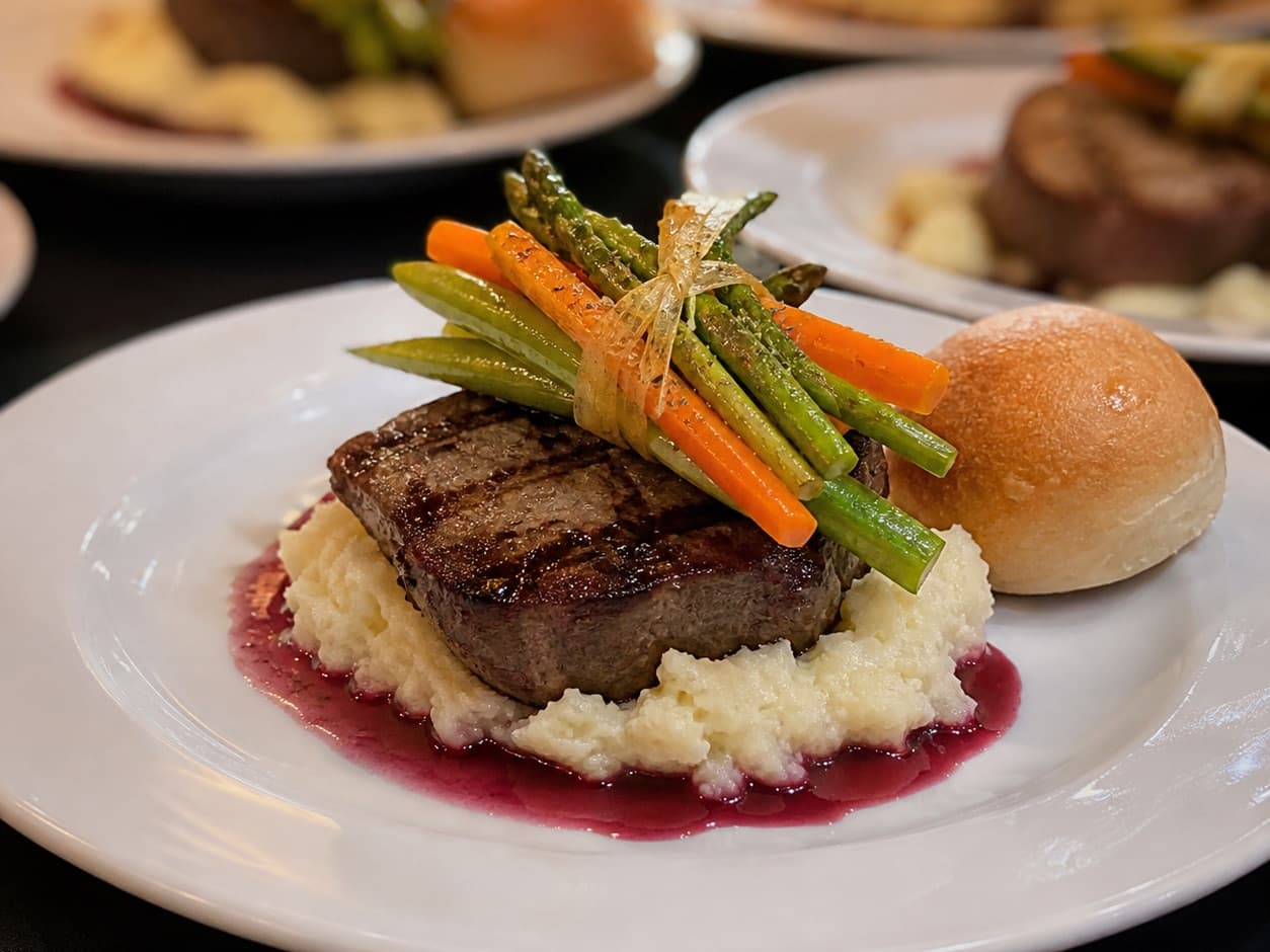 Grilled beef medallion over mashed potatoes with red wine sauce and seasonal vegetables